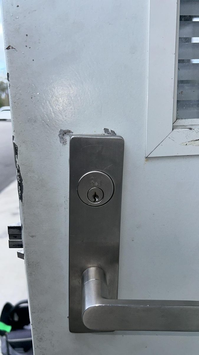Locksmith servicing an exit device on a commercial door