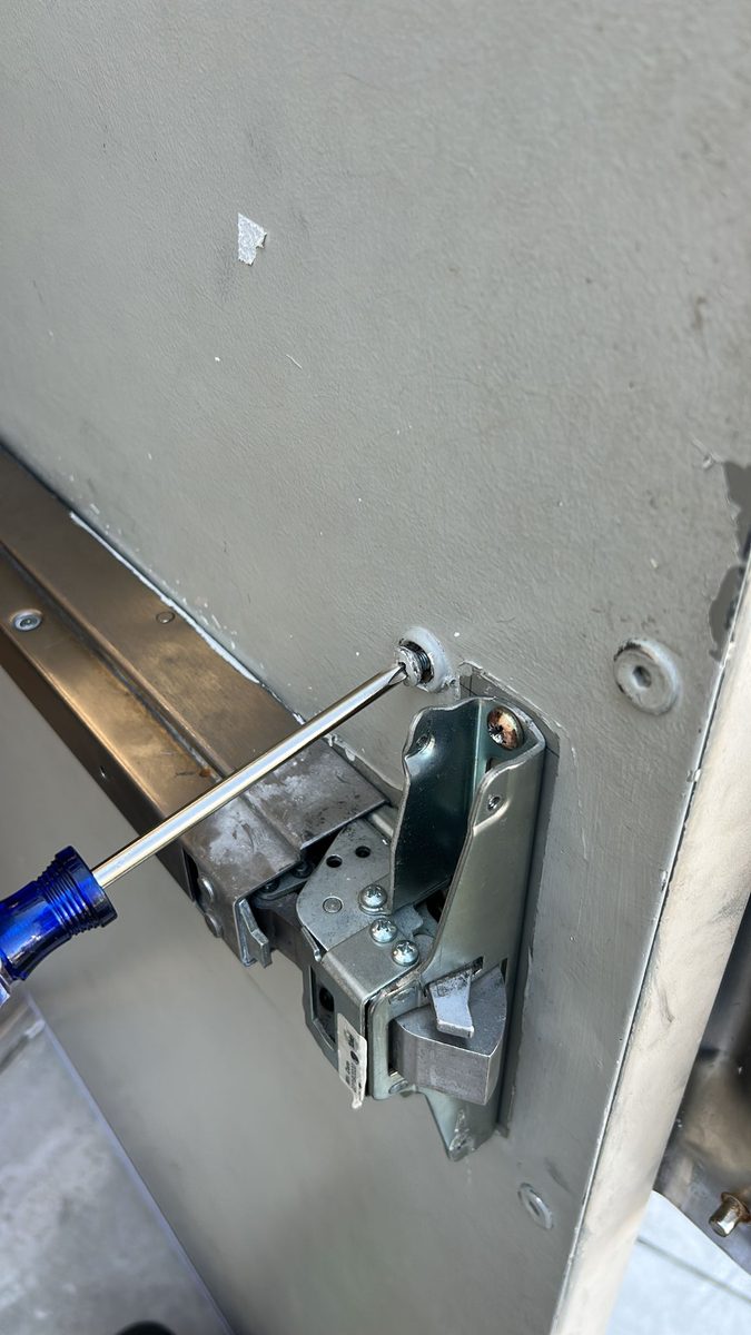 Locksmith repairing a panic bar on a commercial exit door